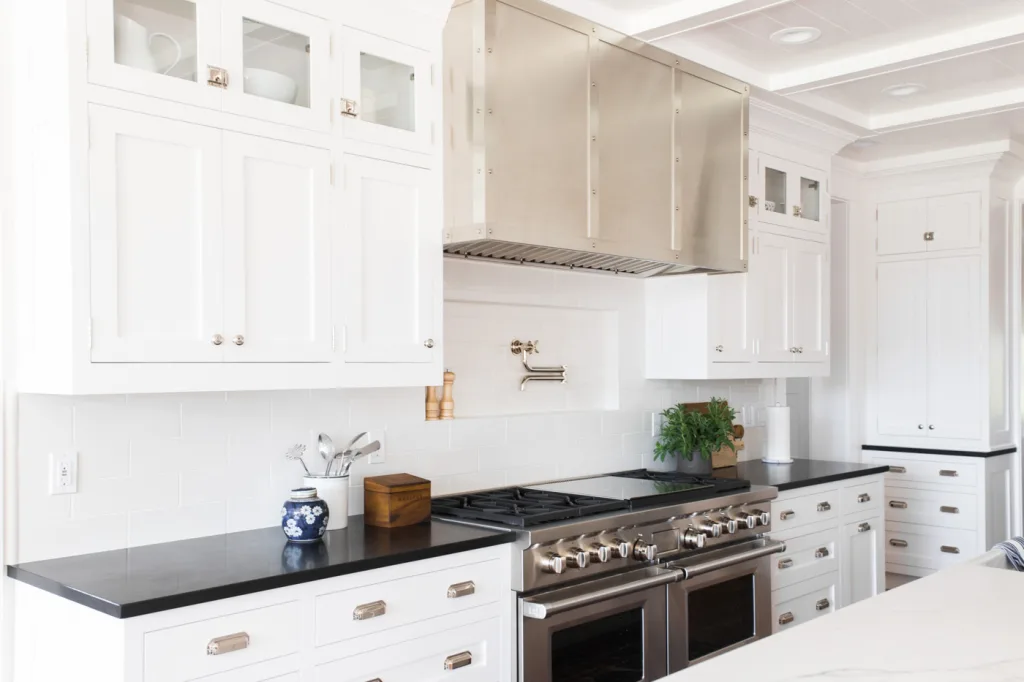 White kitchen with subway tile niche, black countertops and indoor greenery to soften